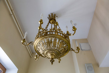 Old forged chandelier with multiple bright lamps
