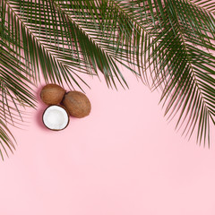 Palm leaves and coconuts whole and halves of coconut on a pink pastel background