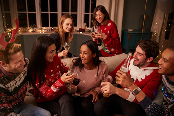 Friends In Festive Jumpers Celebrate At Christmas Party