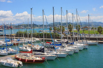 Fototapeta na wymiar Yacht parking. Italian Riviera. Different yachts on the background of the sea and the city. The mountains