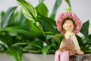 a souvenir statuette of a girl sitting on a background of foliage