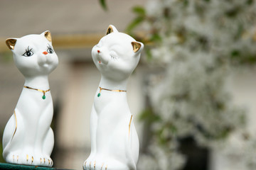 Two cats statuettes against the background of cherry blossoms