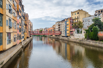 Naklejka na ściany i meble Cloudy view of riverside and bridge over river Onyar, Girona, Catalonia, Spain.