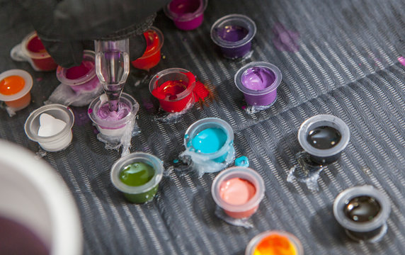 Tattoo artist mixing colors into small cup for ink