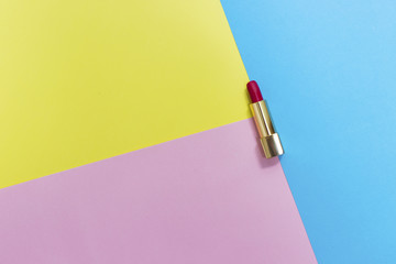 Top view of makeup set: red lipstick on pastel background.