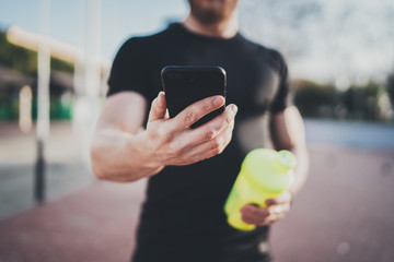 Smart workout session concept.Young Muscular athlete checking training programm on smartphone...