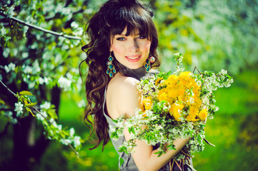 Naklejka premium spring juicy healthy woman portrait on green background with delicate flowers, luxurious curly hair and green brown eyes yellow dandelions in the hands