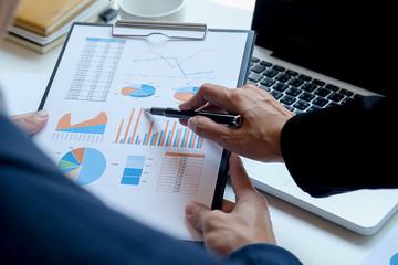 Business concept. Business people discussing the charts and graphs showing the results of their successful teamwork. Selective focus.
