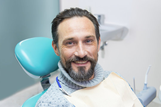 Smiling Man In Dental Chair. Person At The Dentist. Trust Your Smile To Professionals.