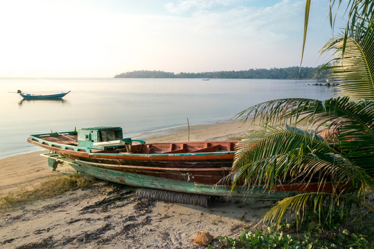 Old broken longtail boat on the Thai beach during the sunset