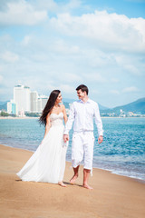 Fototapeta na wymiar Newly married couple after wedding in luxury resort. Romantic bride and groom relaxing near sea. Honeymoon.