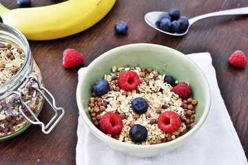 Breakfast bowl with fresh berry fruits. Cereals with blueberries and raspberries on a wooden table.