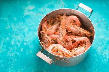 Big shrimps in the metal pot on the cyan background