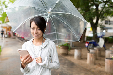 Woman use of mobile phone in rainy day