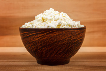 Fresh cottage cheese in bowl on a wooden