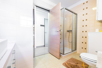Modern small hotel bath with shower, sink and toilet.
