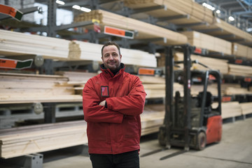 Portrait of confident salesman standing arms crossed at hardware store warehouse