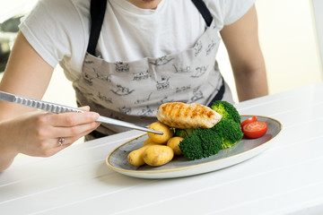 concentrated female chef garnishing food in the kitchen