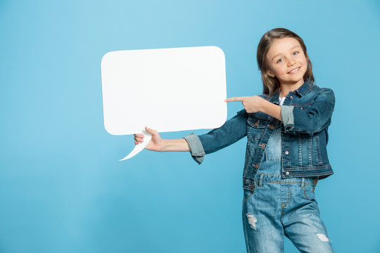 Happy Little Girl Holding Speech Bubble And Pointing With Finger At Copy Space