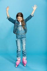 little girl in pink roller skates in studio on blue