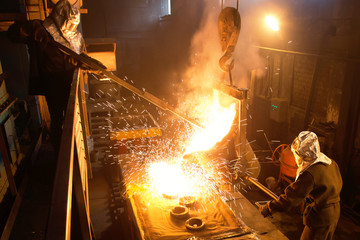Workers operates at the metallurgical plant. Melting Iron in the foundry. Liquid metal in the...