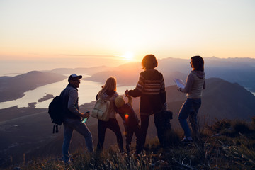 Group of friends on a mountain top enjoying the view and sunset