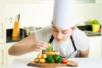 concentrated female chef garnishing food in the kitchen