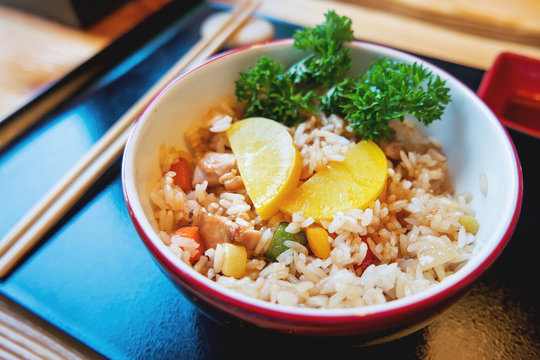 Asian cuisine - Tori tyahan. Fried rice with chicken meat, vegetables and radishes in bowl.