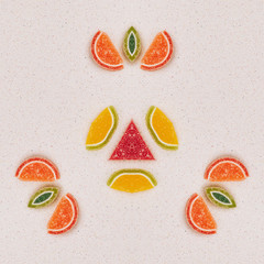 Mandala made from fruit made from marmalade. The pattern is on the gray table top. View from above