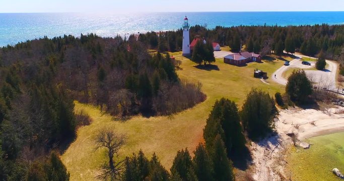 Scenic Lighthouse stands tall on rocky peninsula, breathtaking aerial view.
