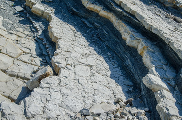 Colorful layered rocky slope of southern mountain and small vegetation