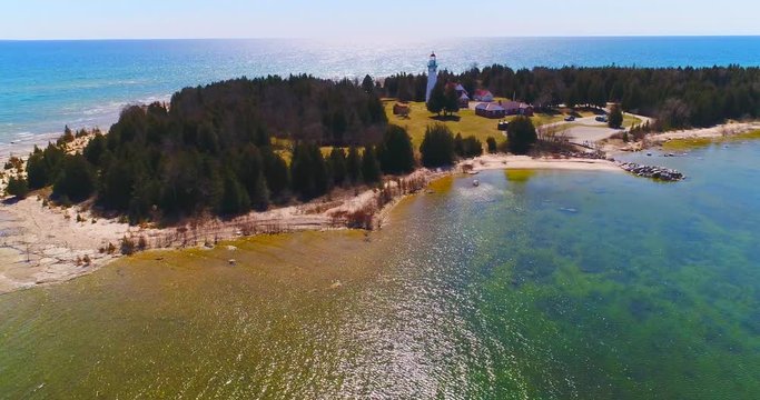 Scenic Lighthouse stands tall on rocky peninsula, breathtaking aerial view.
