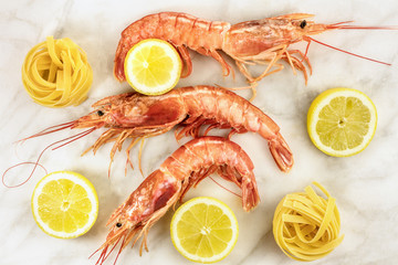 Raw shrimps with lemon and pasta on marble table