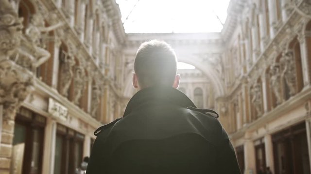 Young confident Caucasian male walking through beautiful passageway in Odessa. Back view in slowmotion
