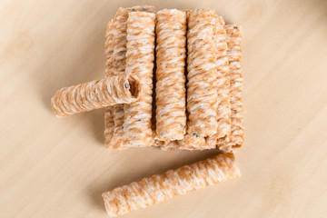 Crispy rolled wafer sticks, traditional dessert in Thailand, are collocated on the wood board.