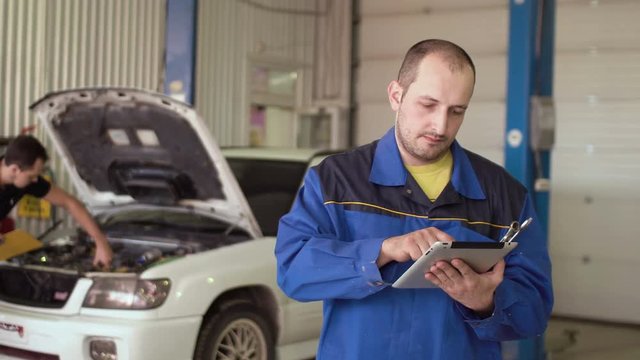car mechanic using tablet touch screen on a car cepair service