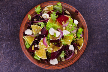 Fototapeta na wymiar Mozzarella, Orange, Beetroot, Red Onion, Nuts and Seeds Salad. View from above, top studio shot