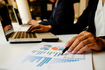 Business concept. Business people discussing the charts and graphs showing the results of their successful teamwork. Selective focus.