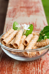 Crispy rolled wafer sticks, traditional dessert in Thailand, are collocated in the transparent bowl.