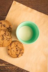 Chocolate chips cookies on baking paper, with milk