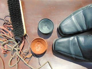 black shiny shoes with shoe polish, shoelaces and a brush 