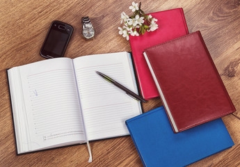 notebooks to write on a wooden background with a clock and a telephone