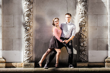 a man and a woman - swing dancers - posing near old concrete wall