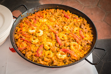 A spanish paella just cooked about to be served at a restaurant somewhere in the spanish coast.