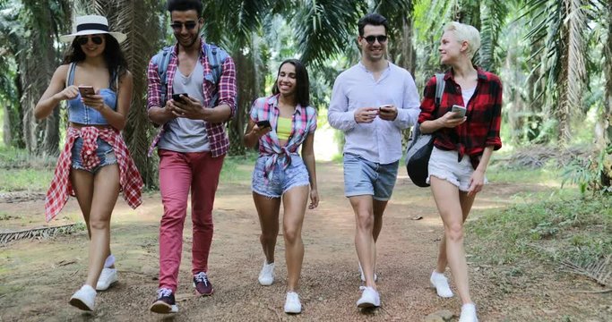 People Group With Backpacks Walking Using Cell Smart Phones, Men And Woman Chatting Online On Trekking In Palm Tree Forest Slow Motion 60