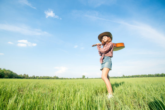 Woman With Guitar Standing In Grass Field