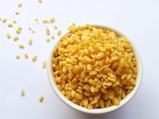 Closeup a white bowl of dried peel split mung bean on white background, selective focus. 