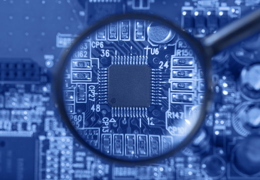 Circuit board with electronic components through a magnifying glass. Computer and networking communication technology concept. Toned image. Low depth of field.