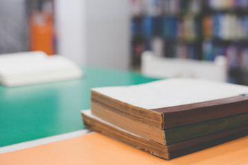 A stack of old books on table with blur book in library, education background