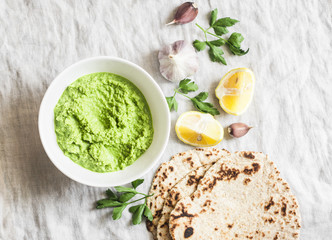 Green avocado dip and gluten free flatbread on a light background, top view. Healthy vegetarian...